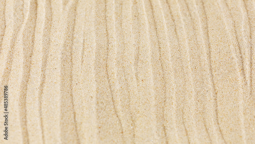 Wavy sand texture background. Dented sande waves of the blow of the wind. Sand wave pattern on a beach
