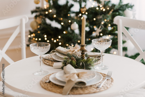 Stylish bright interior of the living room with a Christmas tree and a festive table