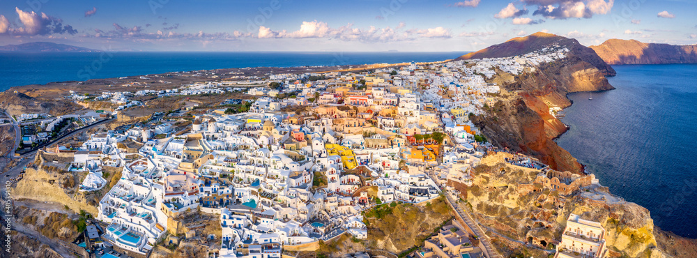 Picturesque Aerial drone view of famous Oia village with white houses during sunrise on Santorini island, Greece, Europe. Luxury travel. Summer holidays. Travel concept background.