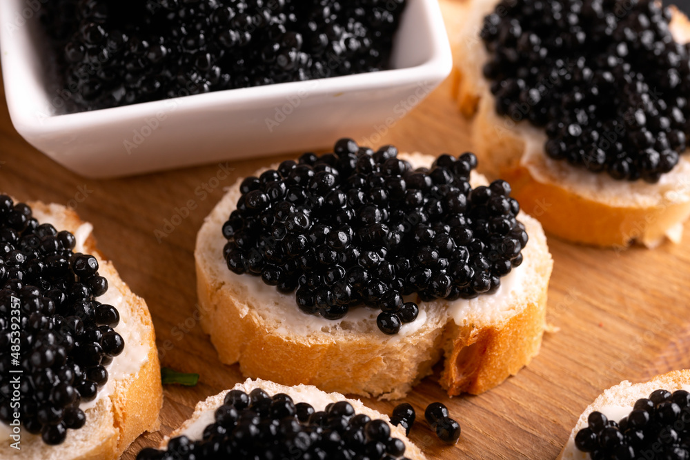 Slices of bread with black caviar on rustic dark background Slices of bread with black caviar on rustic dark background