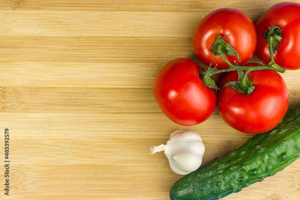 Red tomatoes, green cucumber, garlic on a wooden board Red tomatoes, green cucumber, garlic on a wooden board