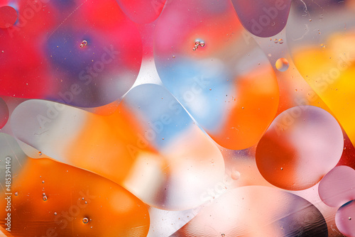 Close-up of the movement of oil droplets on the water surface. Colorful abstract macro background of oil drops on the water surface.