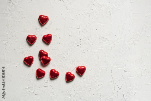 White texture valentine background with red chocolate hearts. Flat lay romantic, space for text