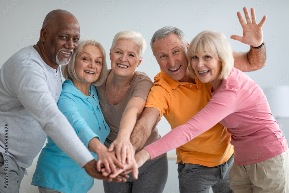 Obraz premium Multiracial group of athletic senior people placing hands