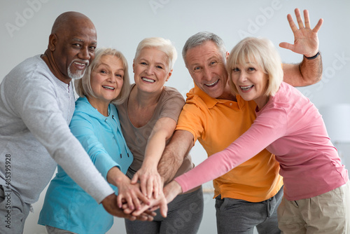 Multiracial group of athletic senior people placing hands photo