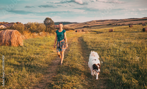 woman with dog walking on meadow