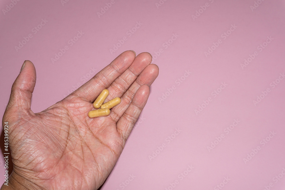 Close up picture of a man hand holding ginger root capsules. Treating nausea and vomiting after surgery, dizziness, menstrual pain, arthritis, preventing morning sickness. Close up picture of a man hand holding ginger root capsules. Treating nausea and vomiting after surgery, dizziness, menstrual pain, arthritis, preventing morning sickness.
