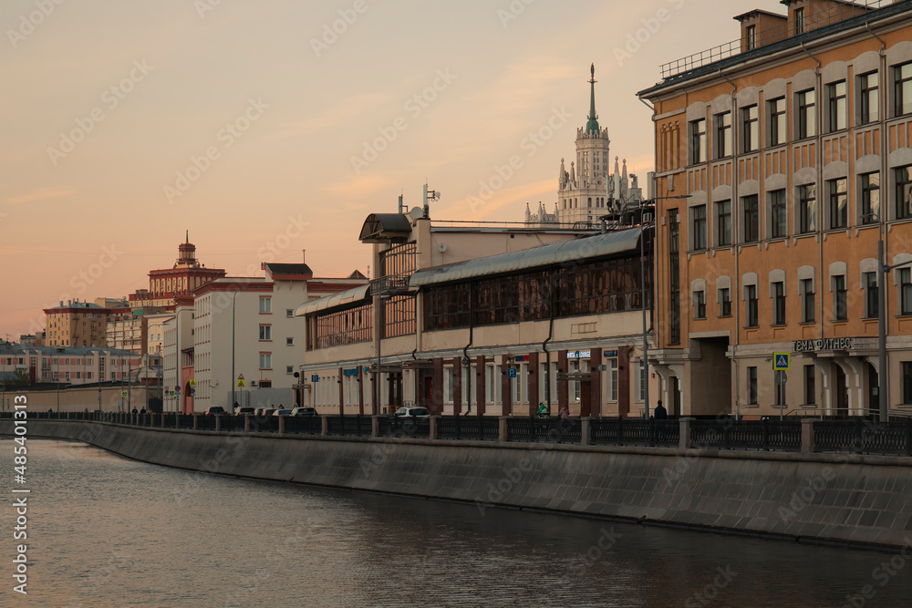 A river in front of an embankment against a Moscow cityscape at autumn sunset