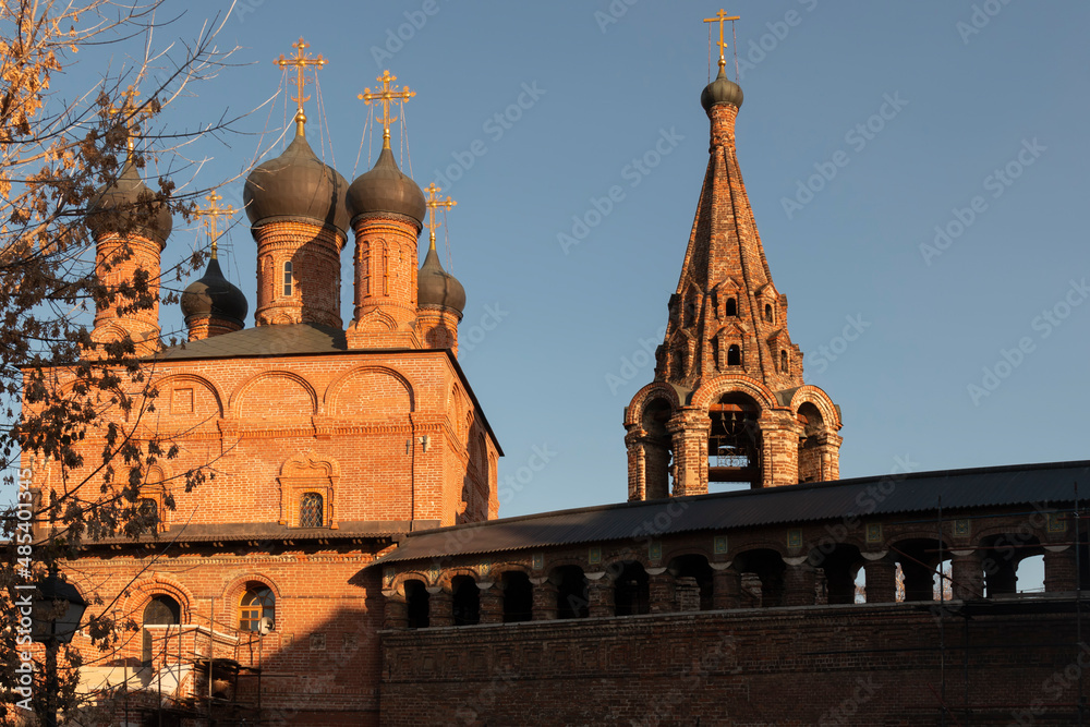 The Dormition Cathedral and a bell tower in the Krutitsy Metochion against the sky by autumn day