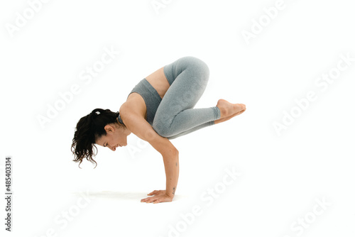 Woman doing yoga asana in white background. Black outfit. Ashtanga, Vinyasa, Hatha