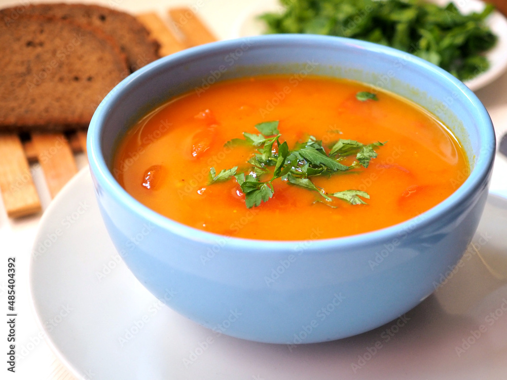 Vedic cooking. Vegetarian pumpkin soup with fresh herbs in a blue bowl. Close-up Vedic cooking. Vegetarian pumpkin soup with fresh herbs in a blue bowl. Close-up