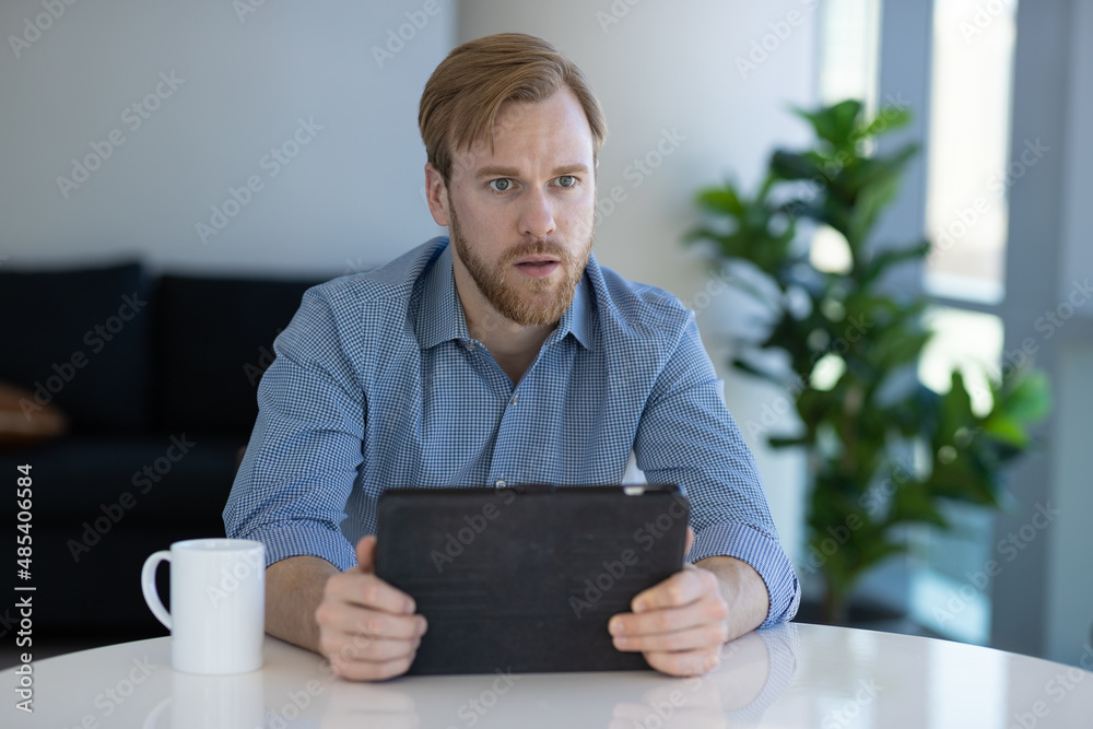 Caucasian man at home using a tablet computer Caucasian man at home using a tablet computer