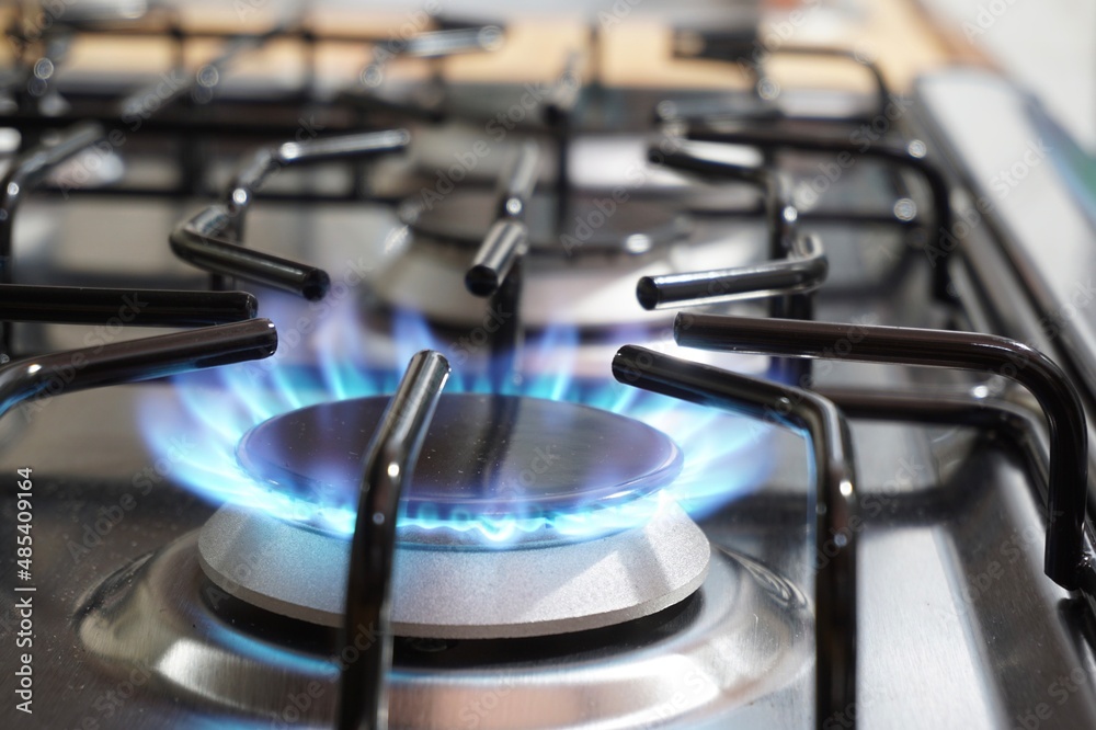 Closeup of a black kitchen burner with fire on a stove Closeup of a black kitchen burner with fire on a stove