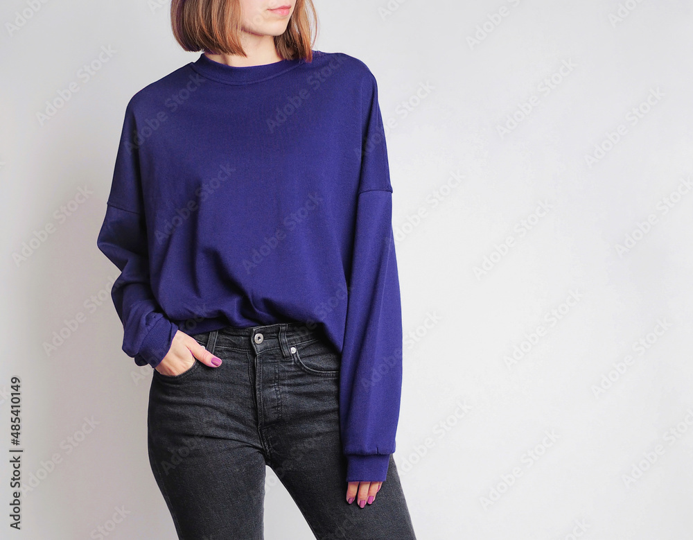Young woman wearing oversized sweatshirt and black high-waisted jeans  isolated on white background. Copy space Stock Photo | Adobe Stock