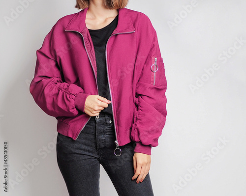 Foto Woman wearing pink bomber jacket and black jeans isolated on white background