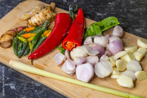 Thai green curry paste ingrediant including chillies  galangal  chinese key  lemongrass  shallots  garlic  tumeric  kaffir lime leafs  red peppers  red curry on a wooden board