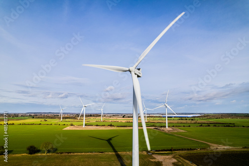 Aerial shot of wind farm turbines with blue cloudy sky, UK