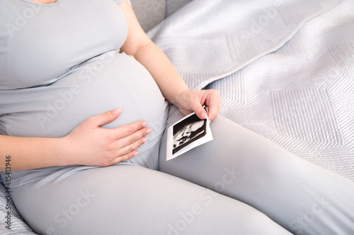 Closeup of a pregnant woman holding belly and sonogram of the baby.Concept of motherhood