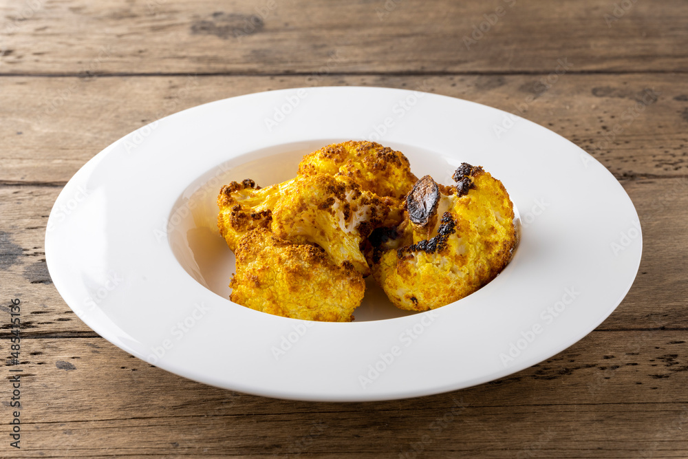 baked cauliflower with curry on white plate baked cauliflower with curry on white plate