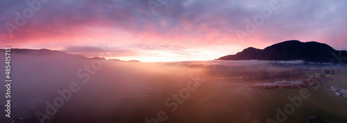 Aerial Panoramic View of Farm lands and Canadian Mountain Nature Landscape. Dramatic Winter Sunset. Located near Chilliwack and Abbotsford, British Columbia, Canada.