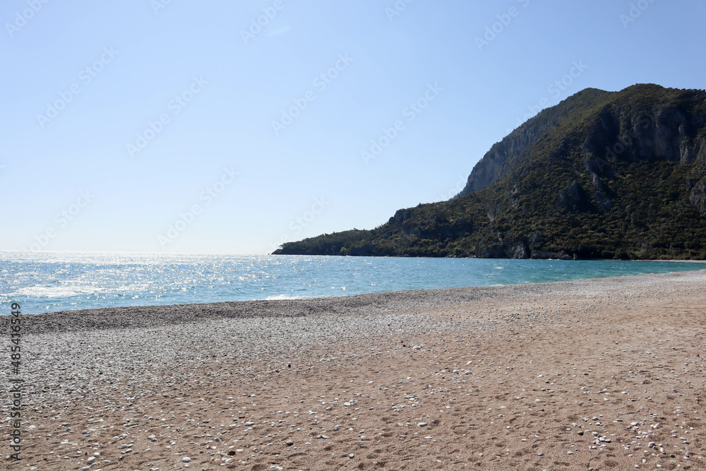 pebble beach of Cirali, Turkey and mediterranean sea with mountain and clouds in spring sunny day