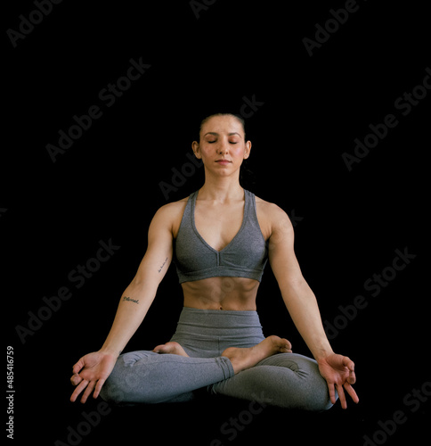 Woman doing yoga asana meditation lotus in black background. Ashtanga, Vinyasa, Hatha