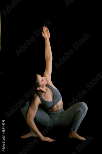 Woman doing yoga asana in black background. Ashtanga, Vinyasa, Hatha