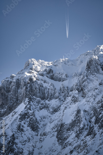 Karwendel - winter landscape with snow covered mountains, rocks, blue sky and air plane