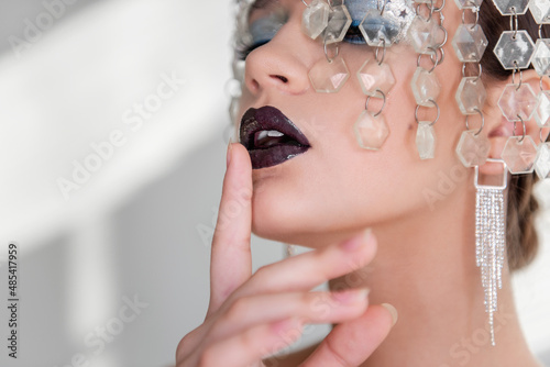 Fashion beauty close-up portrait of girl with black glossy lips, blue eyeshadows. crown of crystals