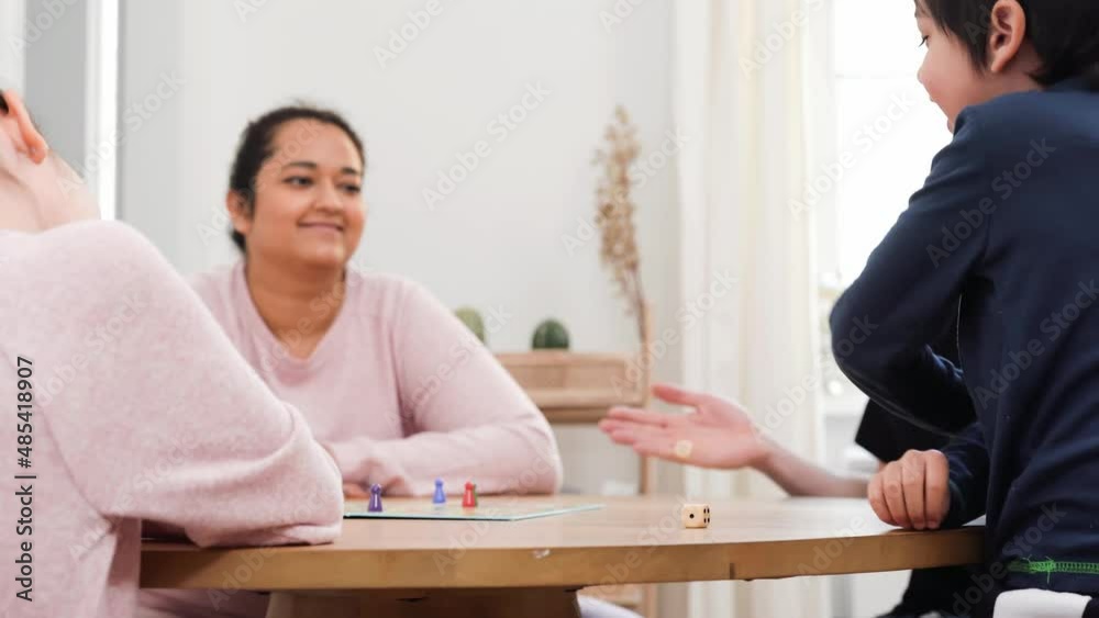 Mixed race family sitting together at the table and playing with board game. They think and concentrate. Real life, diversity, digital detox and unplugging from technology. 4K UHD Mixed race family sitting together at the table and playing with board game. They think and concentrate. Real life, diversity, digital detox and unplugging from technology. 4K UHD
