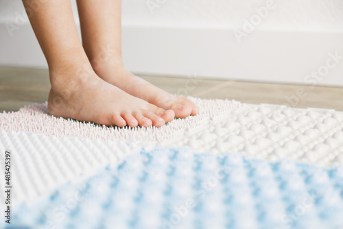 child's feet on an orthopedic mat, exercises for legs orthopedic massage carpet, orthopedic massage puzzle floor mats with colorful details for preventing flatfoot, close up photo