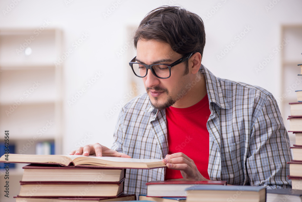 Young male student and too many books in the classroom