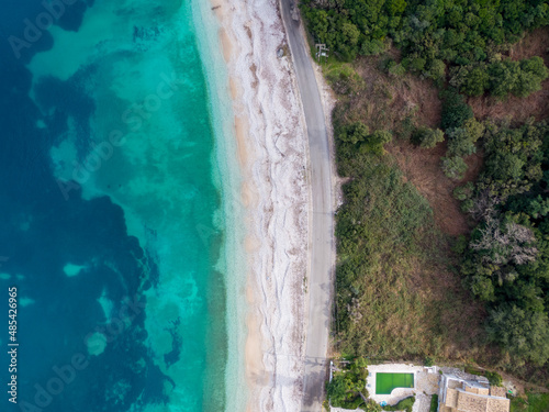 Top-down aerial view of a clean white sandy beach on the shores of a beautiful turquoise sea in corfu Greece