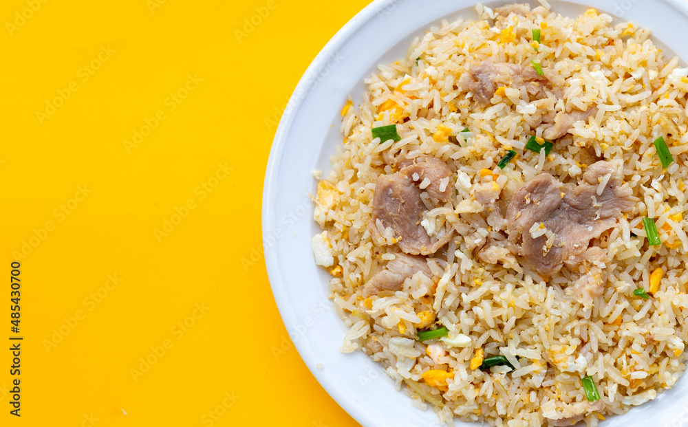 Fried rice in white plate on yellow background.