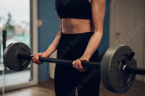 Cropped shot of an athletic woman lifting barbell while training in the gym