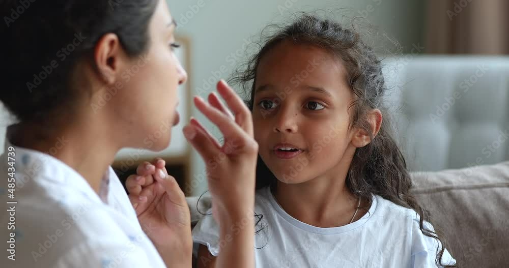 Close up stuttering 6s Indian girl do exercises with speech therapist, train articulation, pronounces repeat words correctly, engaged in voice pronunciation class together at home. Development concept Close up stuttering 6s Indian girl do exercises with speech therapist, train articulation, pronounces repeat words correctly, engaged in voice pronunciation class together at home. Development concept