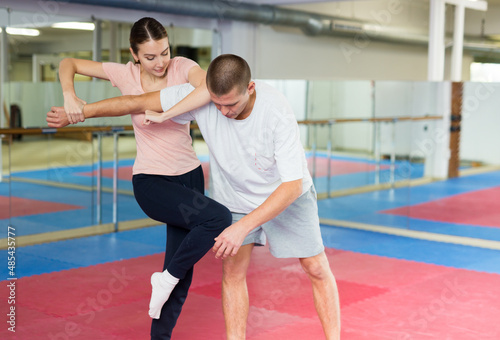 European woman learning knee strike move during self-defense training.