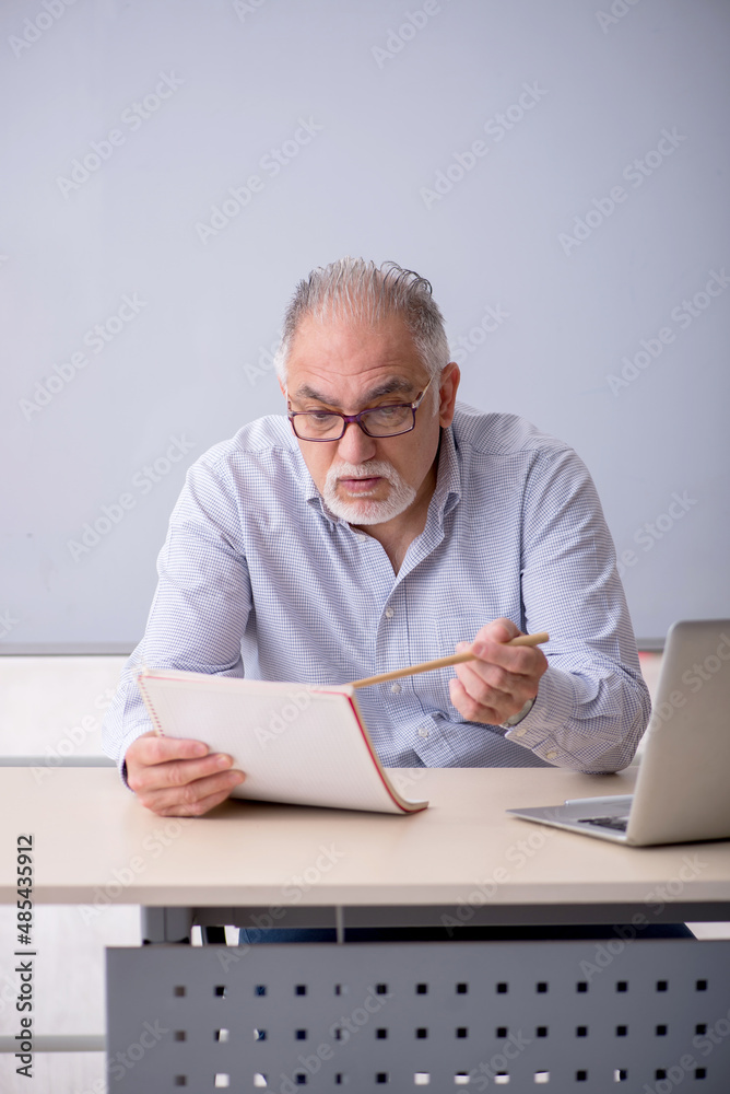 Old male teacher in front of whiteboard Old male teacher in front of whiteboard