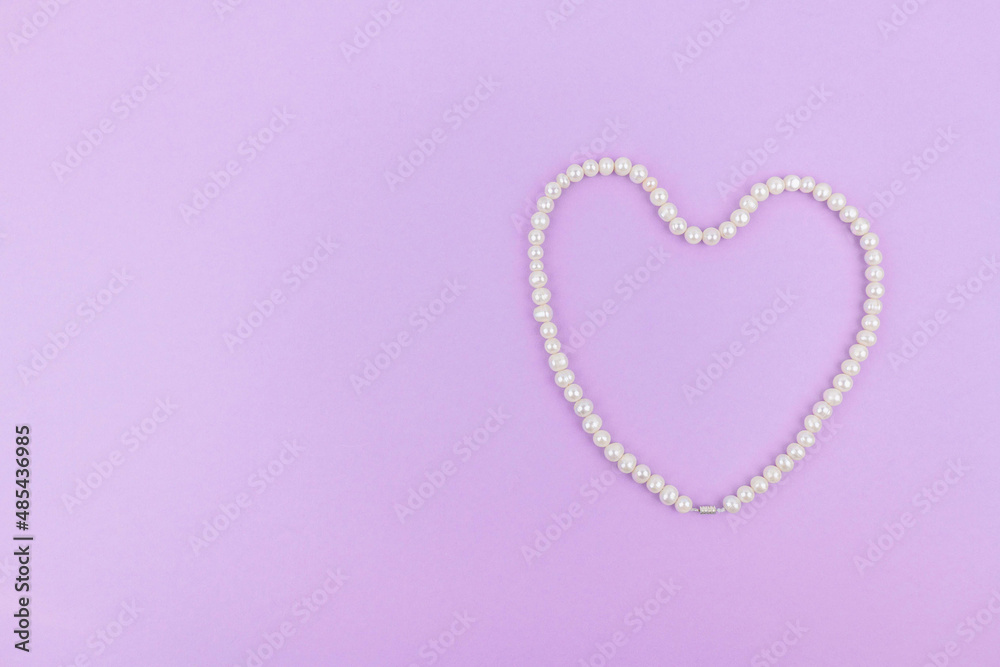 Pearl heart on a lilac paper background. Space for text