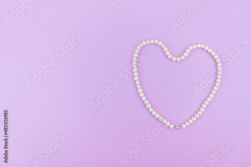 Pearl heart on a lilac paper background. Space for text