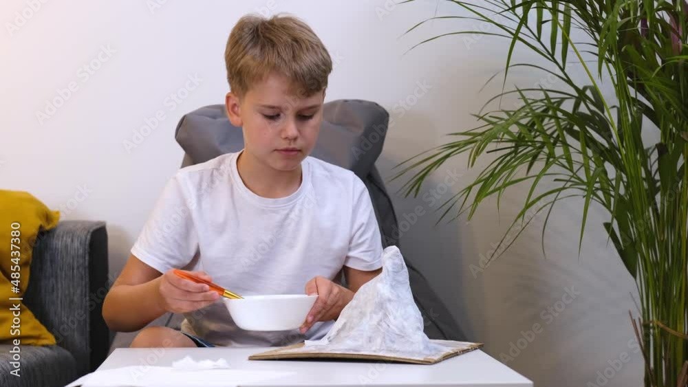 Schoolboy makes creative project in form of papier mache mountain. Schoolboy makes creative project in form of papier mache mountain.