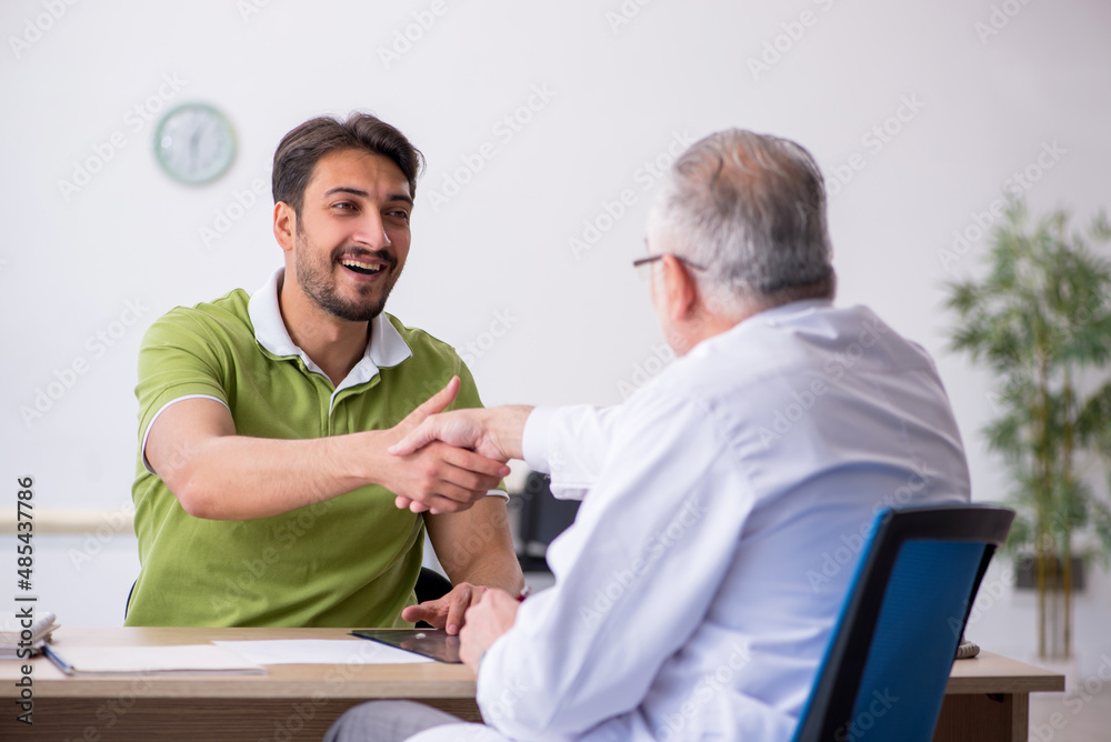 Young man visiting old male doctor Young man visiting old male doctor