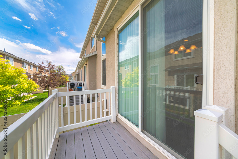 Small deck of a house with sliding glass door and white wood railings