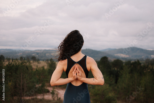 Woman doing yoga exercise asana on a top of a mountain. Prayer namaste hands gesture