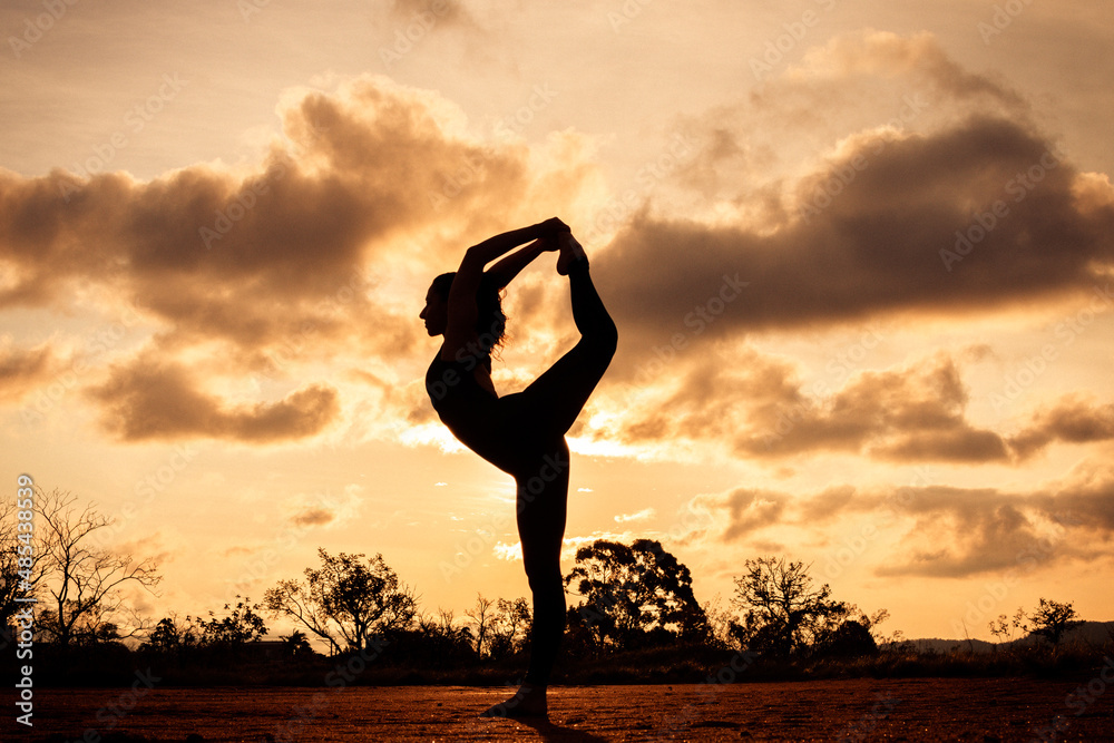 Woman silhouette doing yoga at the sunset.