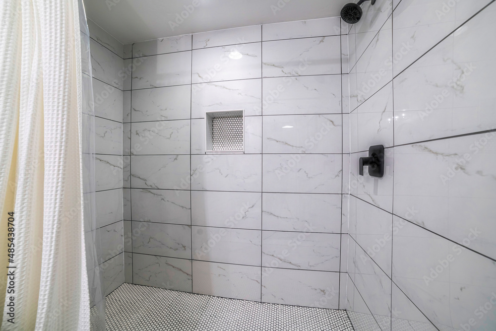 Shower stall with mosaic tiles flooring and marble tiles surround with black grout Stock Photo