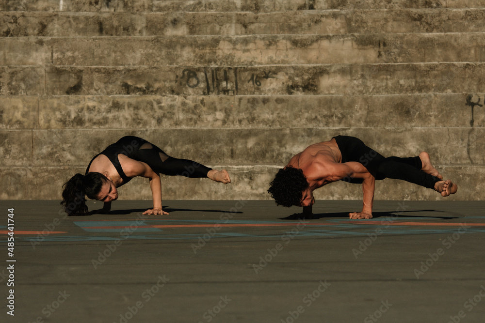 Couple doing yoga fitness exercises sport in the streets with open arms, stairs background. Gratitude and Meditation