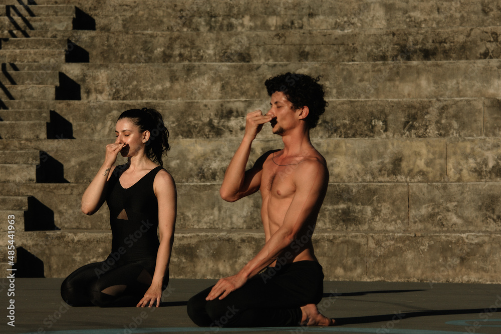 Couple doing yoga fitness exercises sport in the streets with open arms, stairs background. Gratitude and Meditation Couple doing yoga fitness exercises sport in the streets with open arms, stairs background. Gratitude and Meditation