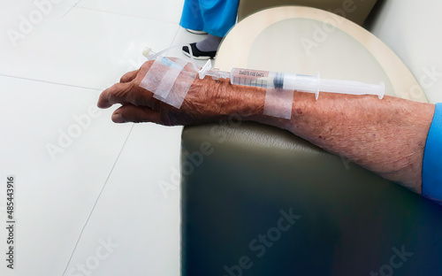 Contrast Injection in a CT Scan, An old woman with a syringe on her hand to inject contrast media into the patient before CT scan. Intravenous injection for CT. Health care and check up concept.