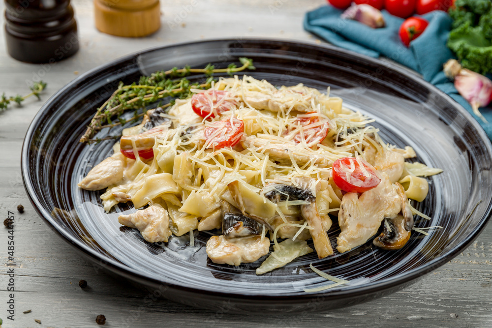 Pasta with chicken and mushrooms on grey wooden table Pasta with chicken and mushrooms on grey wooden table